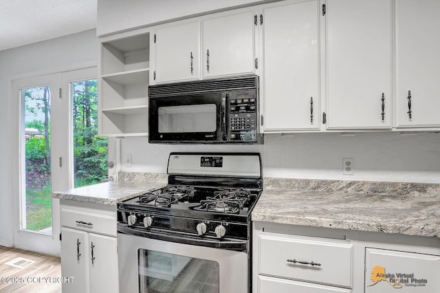 791 N Yakima St, Wasilla, AK 99654 - kitchen with stainless steel gas range oven, black microwave, open shelves, light wood finished floors, and white cabinets