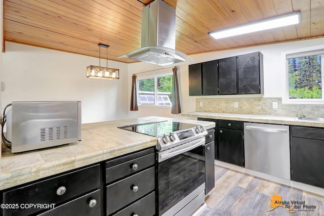 1915 Stanford Dr, Anchorage, AK 99508 - kitchen featuring appliances with stainless steel finishes, island exhaust hood, dark cabinetry, wooden ceiling, and light wood-style flooring