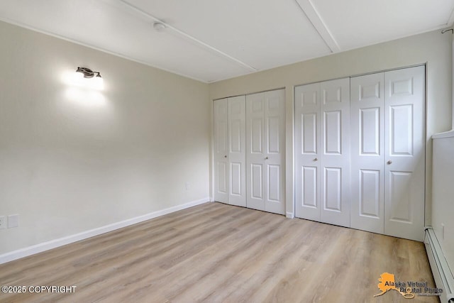 1915 Stanford Dr, Anchorage, AK 99508 - unfurnished bedroom featuring a baseboard radiator, multiple closets, and wood finished floors