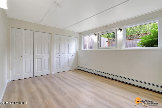 1915 Stanford Dr, Anchorage, AK 99508 - unfurnished bedroom featuring a baseboard radiator, two closets, multiple windows, and wood finished floors