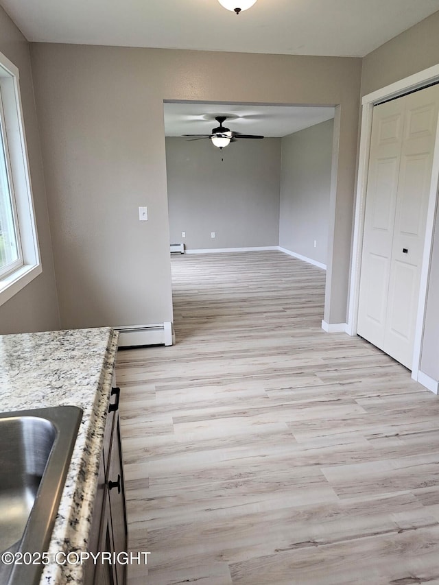 150 S Leibrock St, Soldotna, AK 99669 - kitchen with a ceiling fan, light wood finished floors, a baseboard radiator, and light stone counters