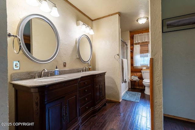 2415 Afognak Ave, Seward, AK 99664 - full bathroom with a textured wall, wood finished floors, double vanity, and bath / shower combo with glass door