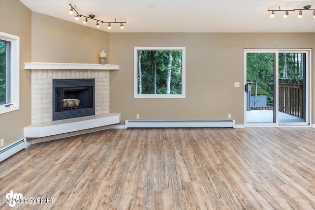 18644 Eaglewood Loop, Eagle River, AK 99577 - unfurnished living room featuring a baseboard radiator, rail lighting, wood finished floors, and a fireplace