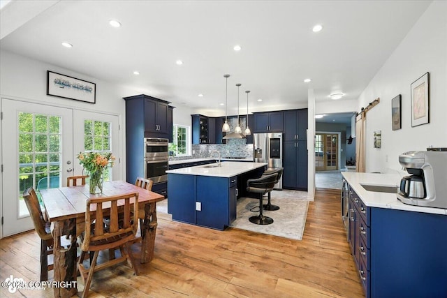 2436 N Hope Cir, Palmer, AK 99645 - kitchen featuring blue cabinetry, stainless steel appliances, light countertops, an island with sink, and light wood-style floors