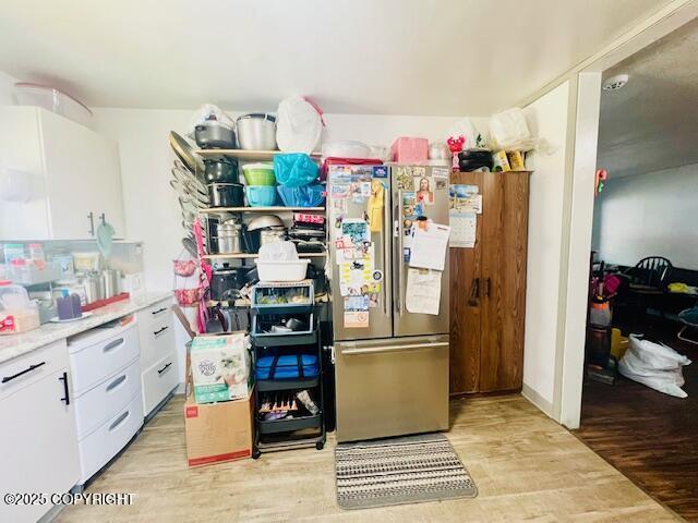 515 Maple Ave, Kodiak, AK 99615 - kitchen featuring freestanding refrigerator, light wood-style flooring, white cabinets, and light countertops