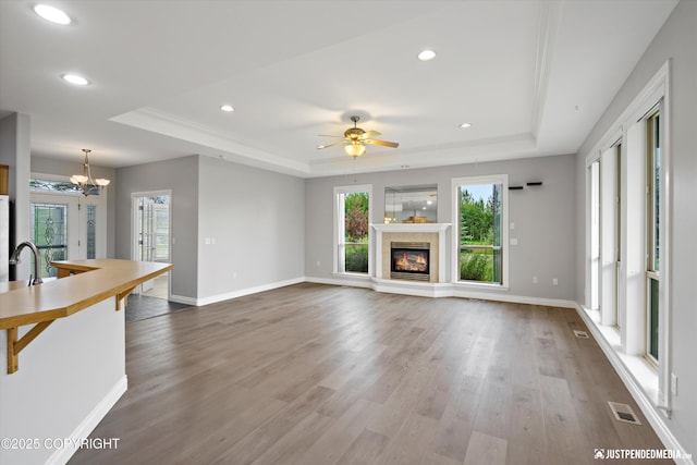 3827 E Country Field Cir, Wasilla, AK 99654 - unfurnished living room featuring a raised ceiling, recessed lighting, wood finished floors, a glass covered fireplace, and a chandelier