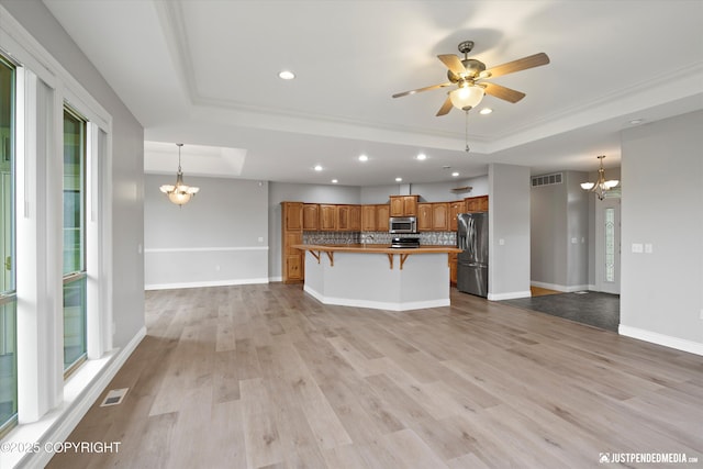 3827 E Country Field Cir, Wasilla, AK 99654 - kitchen with appliances with stainless steel finishes, a tray ceiling, a chandelier, brown cabinetry, and recessed lighting