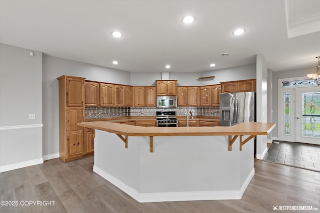 3827 E Country Field Cir, Wasilla, AK 99654 - kitchen with stainless steel appliances, a large island, tasteful backsplash, brown cabinets, and recessed lighting