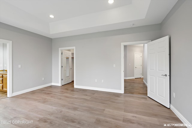 3827 E Country Field Cir, Wasilla, AK 99654 - unfurnished bedroom featuring a raised ceiling, light wood-type flooring, recessed lighting, and a walk in closet