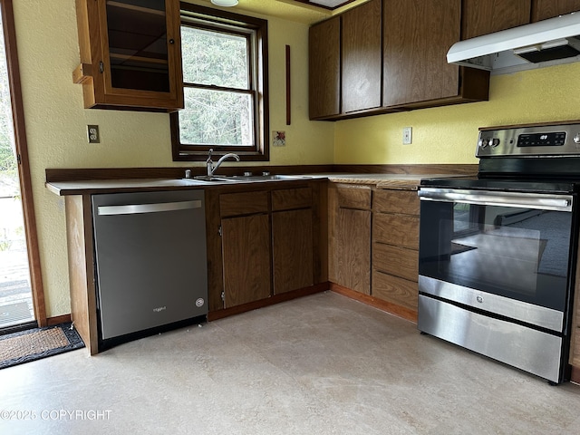 9238 Emily Way, Juneau, AK 99801 - kitchen with stainless steel appliances, under cabinet range hood, a textured wall, dark countertops, and light flooring