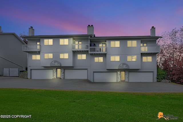 7612 Lumbis Ave # 4, Anchorage, AK 99518 - view of front of property featuring a balcony, a chimney, an attached garage, driveway, and a yard