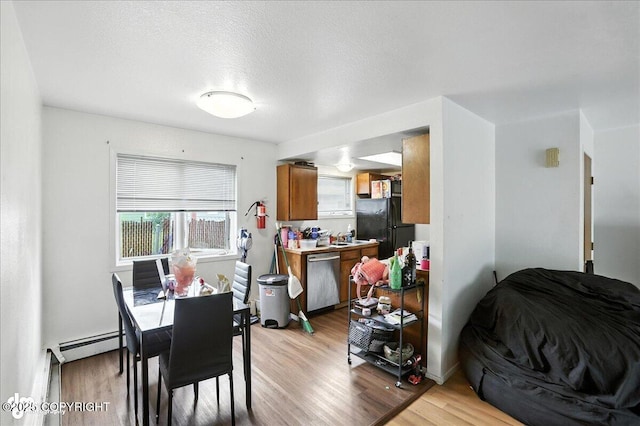 330 N Bliss St, Anchorage, AK 99508 - dining room featuring a baseboard heating unit, light wood-type flooring, and a textured ceiling