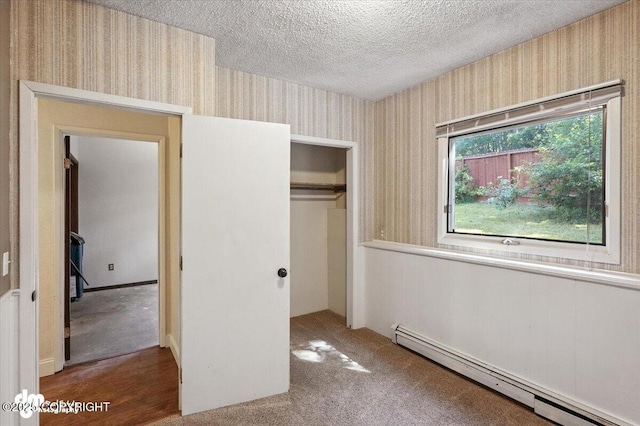 18723 N Lowrie Loop, Eagle River, AK 99577 - unfurnished bedroom with baseboard heating, wallpapered walls, a textured ceiling, a closet, and carpet