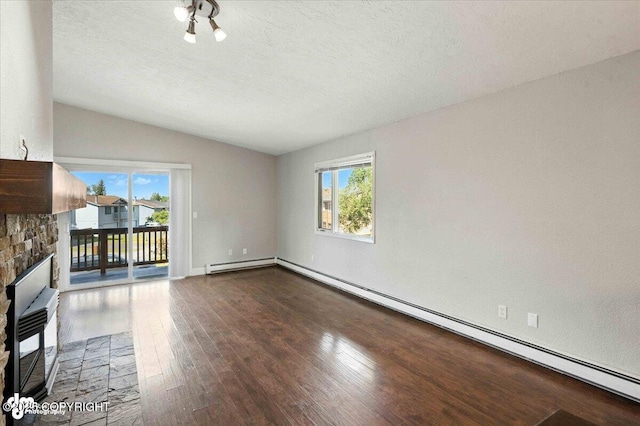 18723 N Lowrie Loop, Eagle River, AK 99577 - unfurnished living room featuring a glass covered fireplace, wood finished floors, plenty of natural light, vaulted ceiling, and baseboard heating