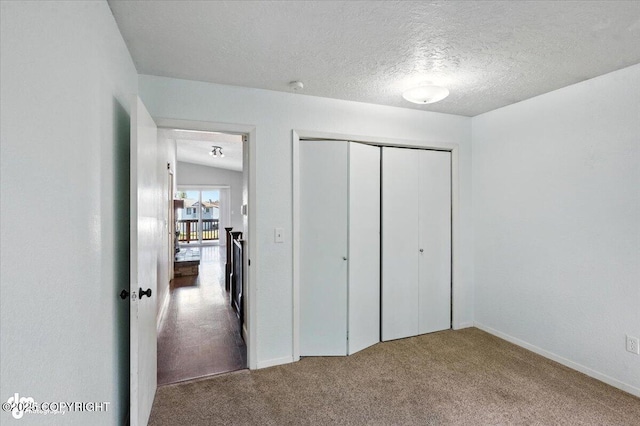 18723 N Lowrie Loop, Eagle River, AK 99577 - unfurnished bedroom with carpet flooring, a closet, and a textured ceiling