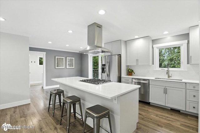 12220 Shiloh Rd, Anchorage, AK 99516 - kitchen featuring appliances with stainless steel finishes, island exhaust hood, ornamental molding, tasteful backsplash, and a kitchen breakfast bar