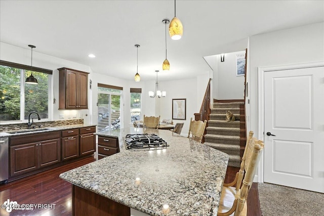 1677 Circlewood Dr, Anchorage, AK 99516 - kitchen with gas stovetop, a kitchen island, a breakfast bar area, a chandelier, and light stone countertops