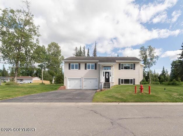 1207 Portside Dr, Kenai, AK 99611 - raised ranch featuring asphalt driveway, an attached garage, and a front lawn