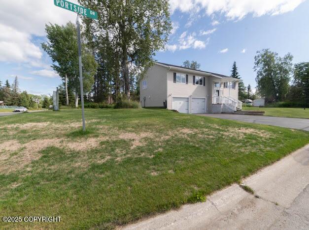 1207 Portside Dr, Kenai, AK 99611 - raised ranch with an attached garage, driveway, and a front yard