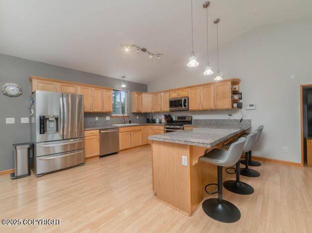 1207 Portside Dr, Kenai, AK 99611 - kitchen with appliances with stainless steel finishes, lofted ceiling, a peninsula, light brown cabinets, and light wood finished floors