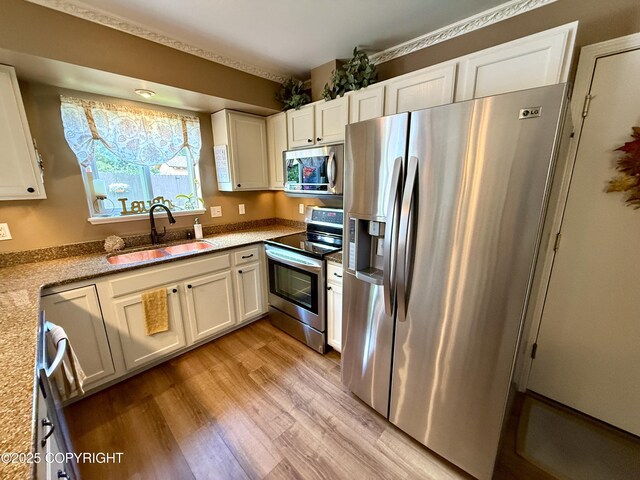 3920 Red Talon Dr, Anchorage, AK 99507 - kitchen with stainless steel appliances, light wood-type flooring, white cabinets, and light stone counters