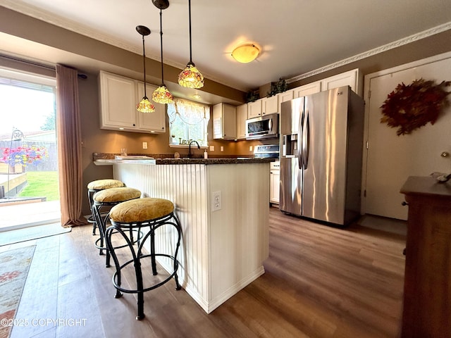 3920 Red Talon Dr, Anchorage, AK 99507 - kitchen featuring appliances with stainless steel finishes, dark wood-type flooring, white cabinetry, plenty of natural light, and ornamental molding