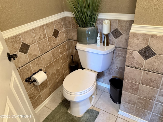3920 Red Talon Dr, Anchorage, AK 99507 - bathroom featuring a textured wall, tile walls, a wainscoted wall, and tile patterned floors