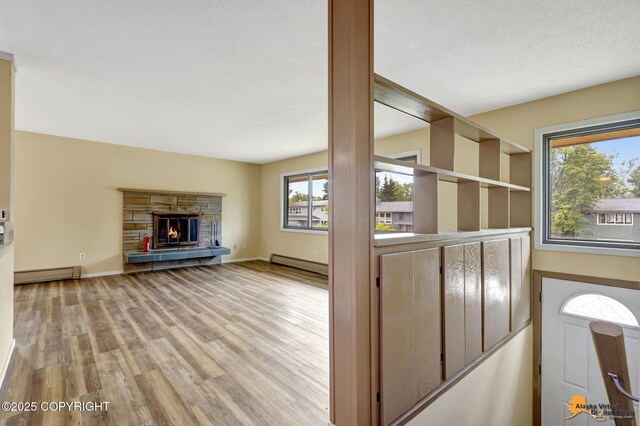 3223 Madison Way, Anchorage, AK 99508 - unfurnished living room featuring baseboard heating, wood finished floors, and a stone fireplace
