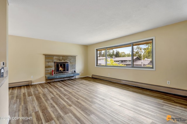 3223 Madison Way, Anchorage, AK 99508 - unfurnished living room featuring a baseboard heating unit, a baseboard radiator, wood finished floors, and a stone fireplace