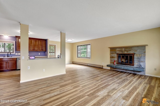 3223 Madison Way, Anchorage, AK 99508 - unfurnished living room with a baseboard heating unit, light wood-type flooring, a fireplace, and a textured ceiling