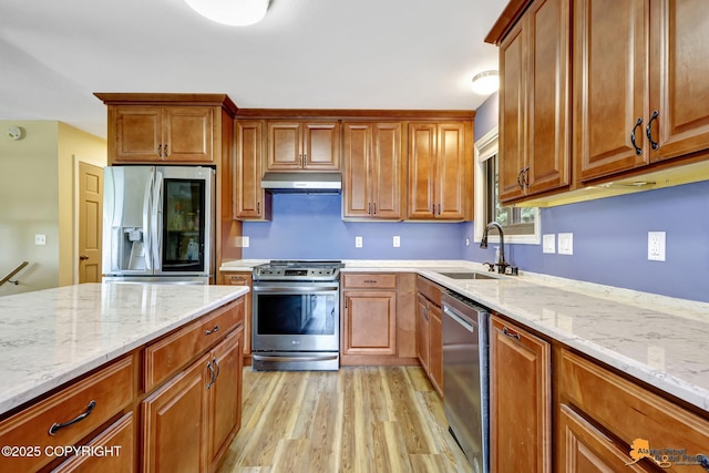 3223 Madison Way, Anchorage, AK 99508 - kitchen featuring appliances with stainless steel finishes, under cabinet range hood, light wood-type flooring, and brown cabinetry