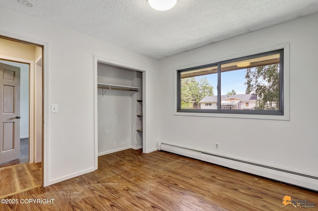 3223 Madison Way, Anchorage, AK 99508 - unfurnished bedroom featuring baseboard heating, wood finished floors, a textured ceiling, and a closet