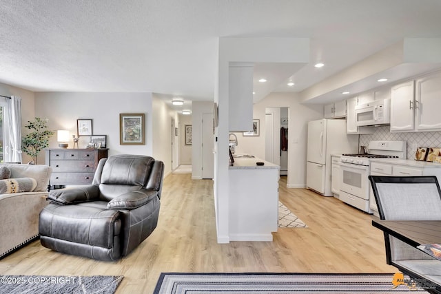 4800 Carousel Cir, Anchorage, AK 99502 - kitchen featuring white appliances, open floor plan, decorative backsplash, white cabinetry, and light wood-style flooring