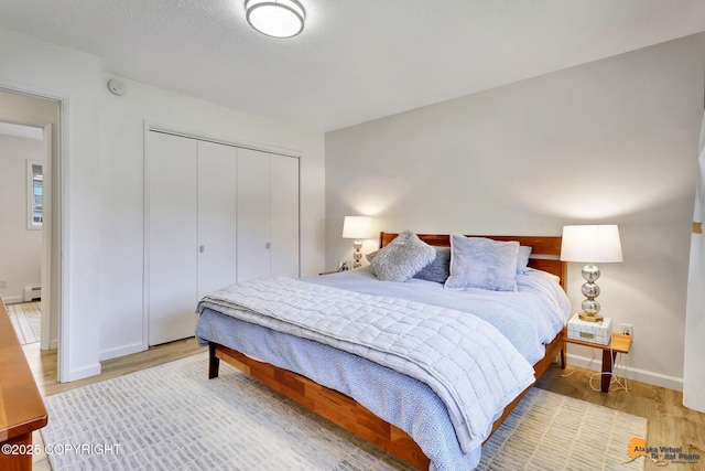 4800 Carousel Cir, Anchorage, AK 99502 - bedroom featuring a closet, light wood-style flooring, and a baseboard heating unit