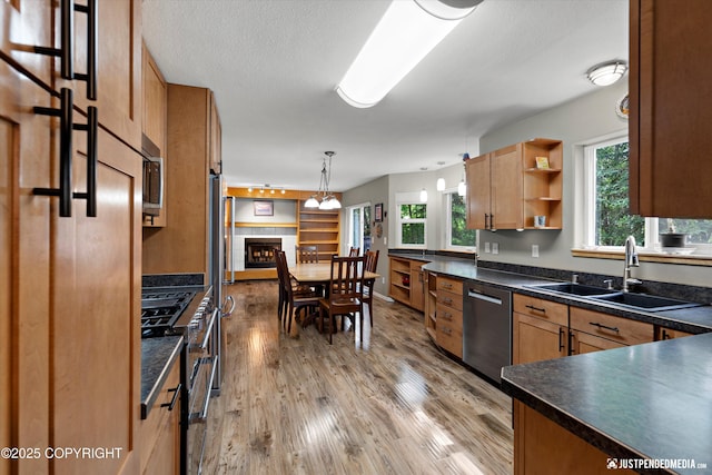 2943 Kingfisher Dr, Anchorage, AK 99502 - kitchen with appliances with stainless steel finishes, dark countertops, light wood finished floors, decorative light fixtures, and a tile fireplace