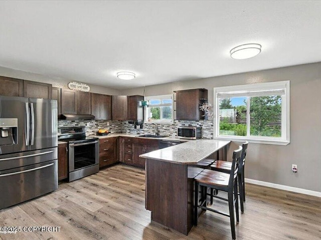 72155 Shannon Rd, Anchor Point, AK 99556 - kitchen featuring stainless steel appliances, dark brown cabinetry, under cabinet range hood, and a breakfast bar