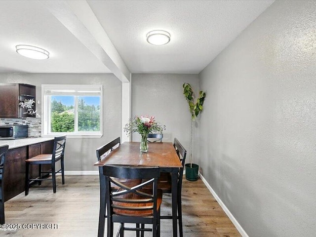 72155 Shannon Rd, Anchor Point, AK 99556 - dining space featuring light wood-type flooring, a textured wall, and a textured ceiling