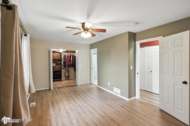 2608 Lauren Creek Loop # 4, Anchorage, AK 99507 - unfurnished bedroom featuring light wood-style floors, a walk in closet, and a ceiling fan