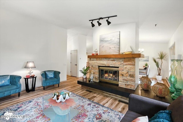 3291 N Edgewater Dr, Wasilla, AK 99623 - living room featuring wood finished floors, rail lighting, and a stone fireplace