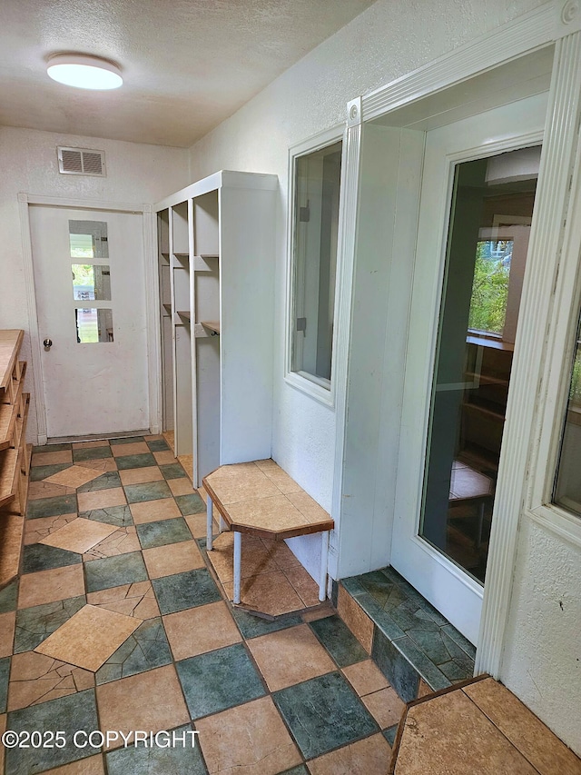 3043 Lakeview Dr, Kodiak, AK 99615 - hallway with a textured ceiling, a textured wall, stone finish flooring, and plenty of natural light