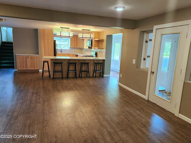 3043 Lakeview Dr, Kodiak, AK 99615 - kitchen featuring dark wood-style floors, light countertops, a kitchen breakfast bar, freestanding refrigerator, and a peninsula