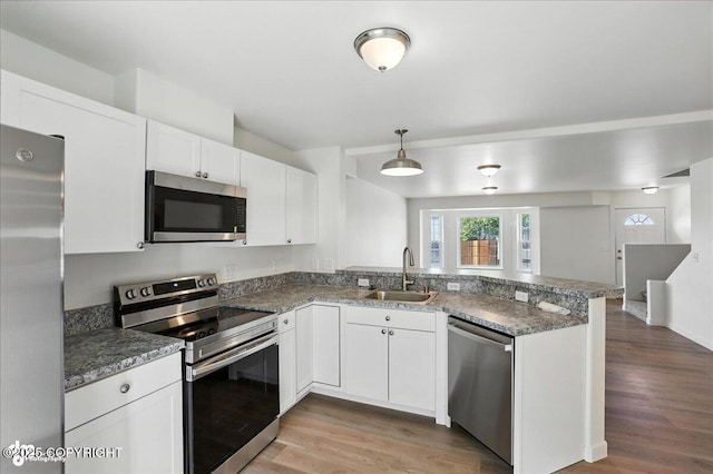 165 Rusty Allen Pl # 64, Anchorage, AK 99504 - kitchen featuring stainless steel appliances, light wood-style flooring, a peninsula, and white cabinets