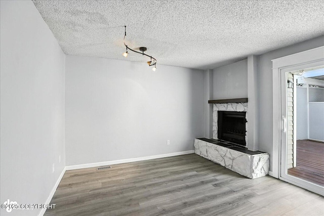 3298 Montpelier Ct Unit 12F, Anchorage, AK 99503 - unfurnished living room with wood finished floors, a fireplace, and a textured ceiling