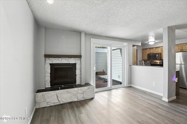 3298 Montpelier Ct Unit 12F, Anchorage, AK 99503 - living room with a stone fireplace, wood finished floors, and a textured ceiling