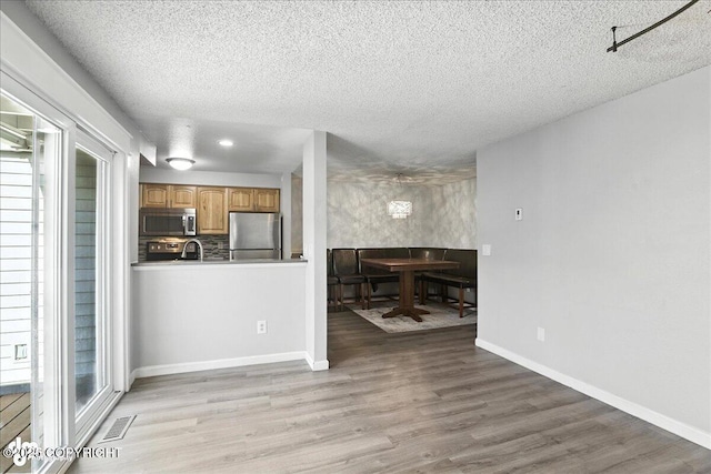 3298 Montpelier Ct Unit 12F, Anchorage, AK 99503 - kitchen with stainless steel appliances, wood finished floors, a textured ceiling, and decorative backsplash