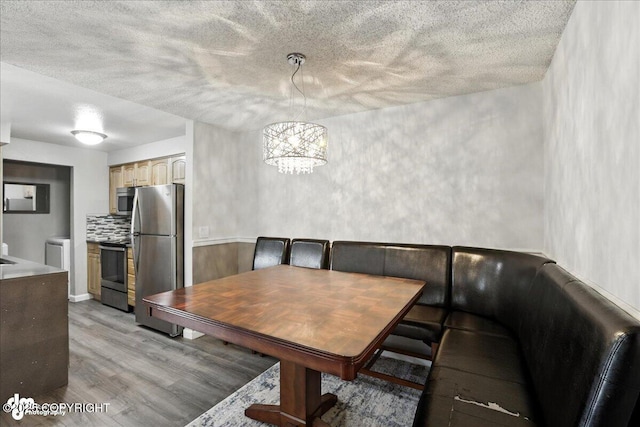3298 Montpelier Ct Unit 12F, Anchorage, AK 99503 - dining area featuring light wood-type flooring, a chandelier, and a textured ceiling