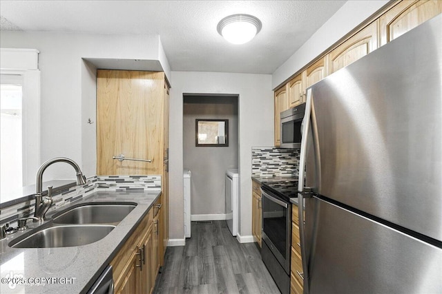 3298 Montpelier Ct Unit 12F, Anchorage, AK 99503 - kitchen featuring appliances with stainless steel finishes, washing machine and clothes dryer, backsplash, dark wood-style flooring, and light stone counters