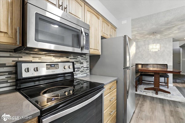 3298 Montpelier Ct Unit 12F, Anchorage, AK 99503 - kitchen with appliances with stainless steel finishes, light brown cabinetry, tasteful backsplash, light countertops, and dark wood-type flooring