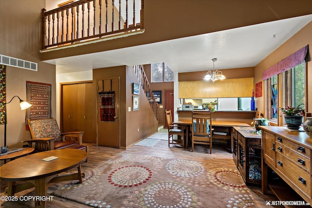 7409 S Timberview Dr, Wasilla, AK 99623 - dining space with light wood-type flooring, a chandelier, stairs, and a towering ceiling