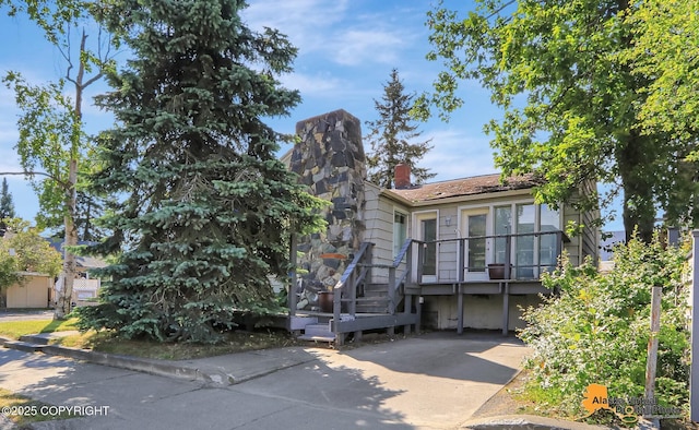 124 E 7th Ave, Anchorage, AK 99501 - view of front of house featuring a chimney, concrete driveway, and a wooden deck